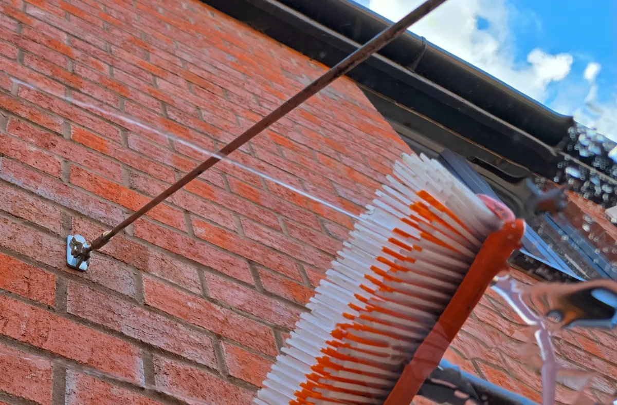 Water-fed pole brush washing a window frame and brickwork with pure water